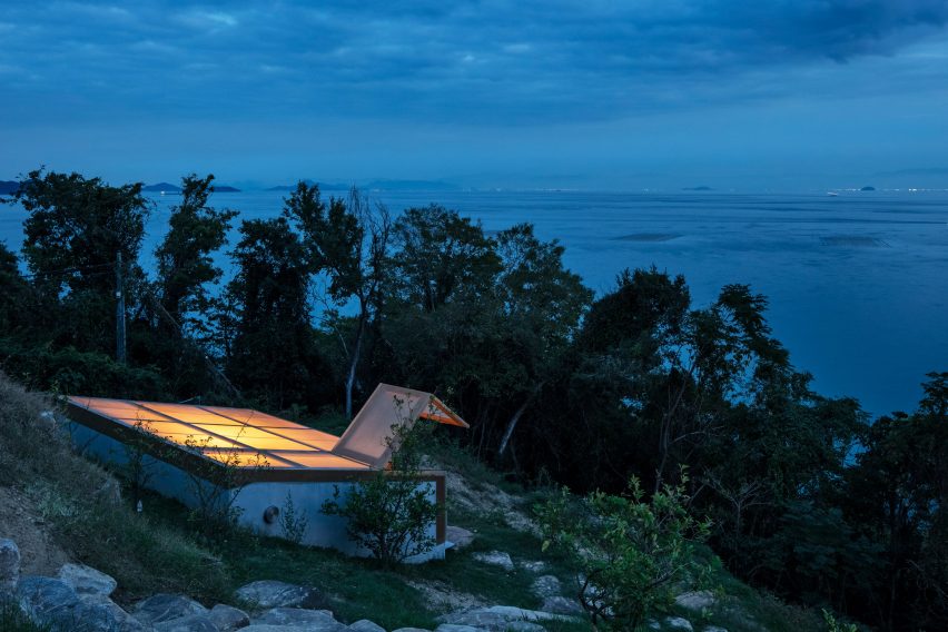 Concrete bunker on a hillside overlooking the sea with a sloped translucent roof