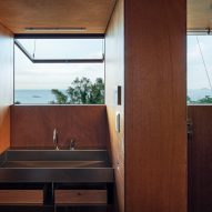 Wood-lined bathroom with a metal sink below an open window