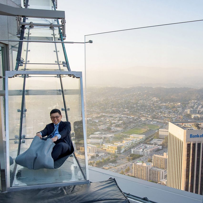 Man sliding down the glass Skyslide overlooking Los Angeles