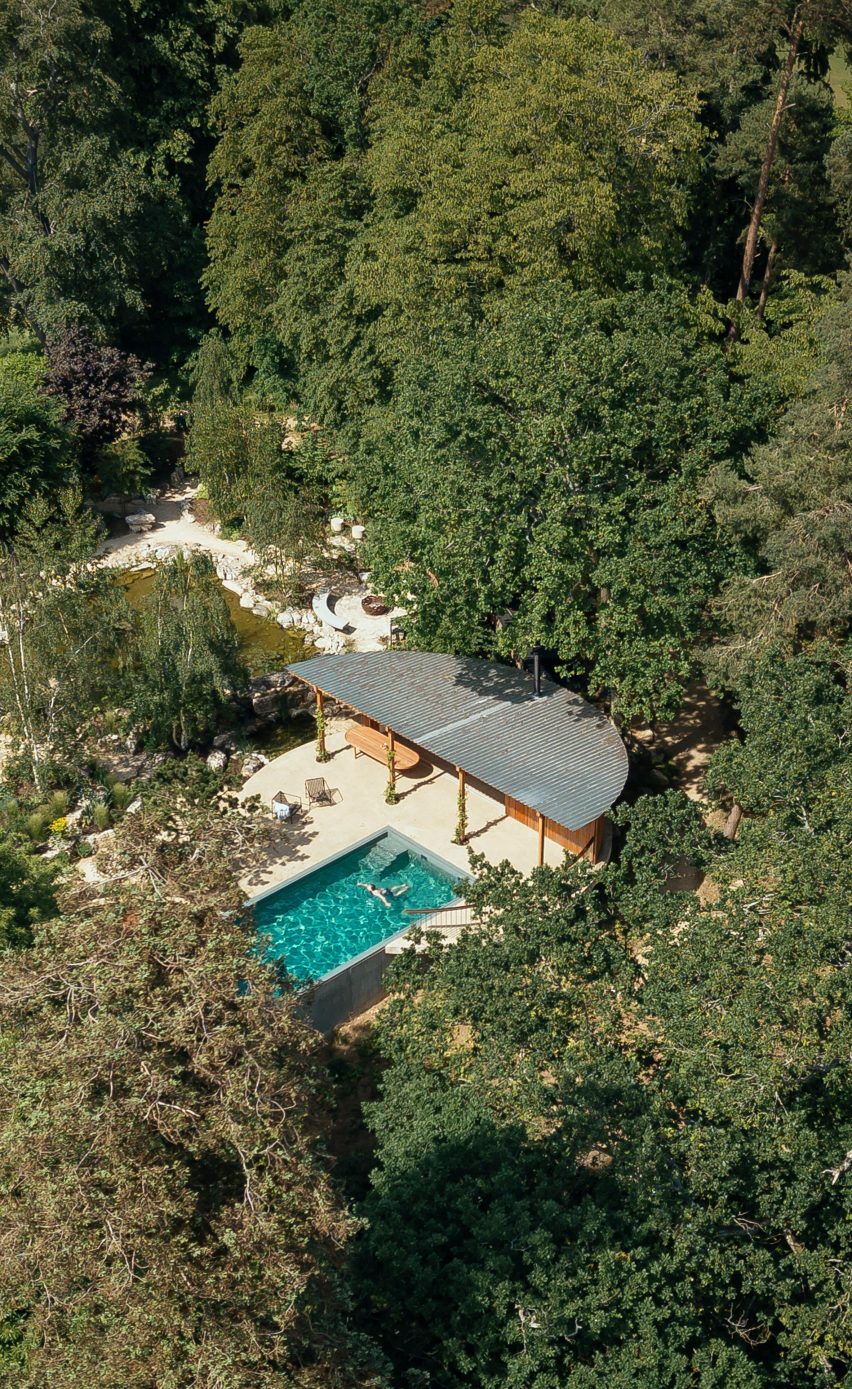 Aerial view of geometric pool house in forested gardens