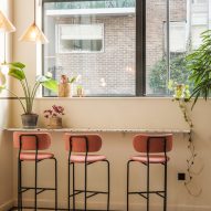 Pink bar stools by a white wall with large windows in metal frames