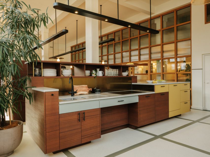 Modular kitchen island in a double-height space with overhead pendant lighting in office interior by The Mint List