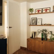 Corner of a room with white walls, parquet flooring, wood side cabinet and shelving