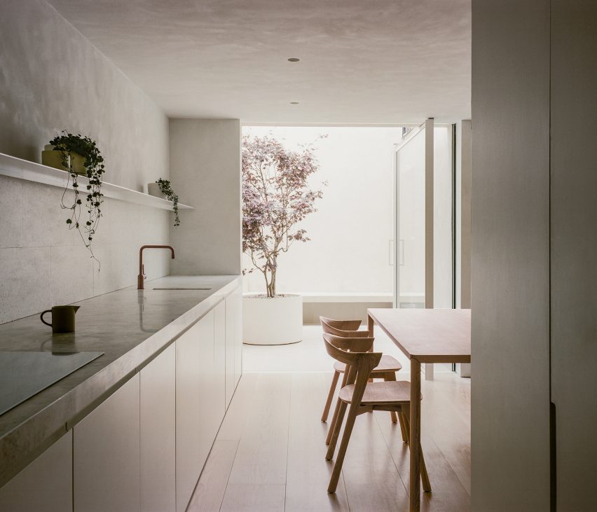 Open plan kitchen and dining space with the kitchen counter on one wall and an outdoor courtyard at the end