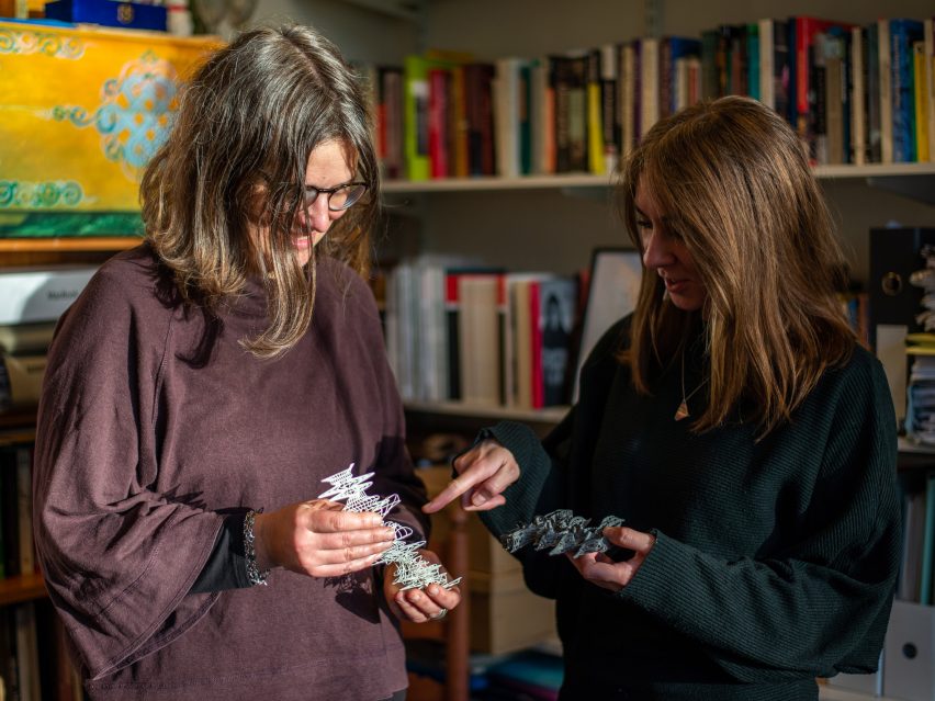 Foto van twee vrouwen die kijken naar 3D-geprinte abstracte objecten die ze in hun handen houden