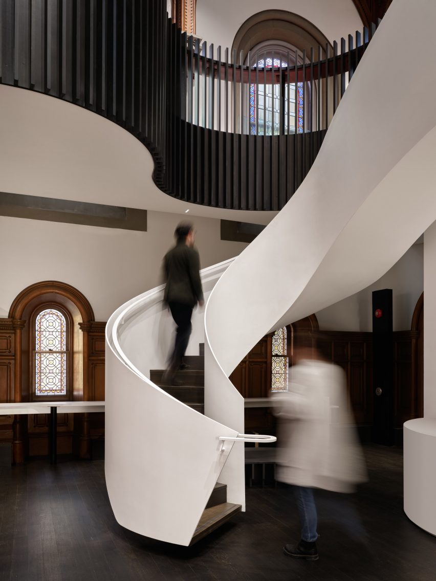 Curved white staircase connects to mezzanine