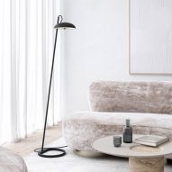 Black floor lamp in a living room with a stone table and curved velvet sofa