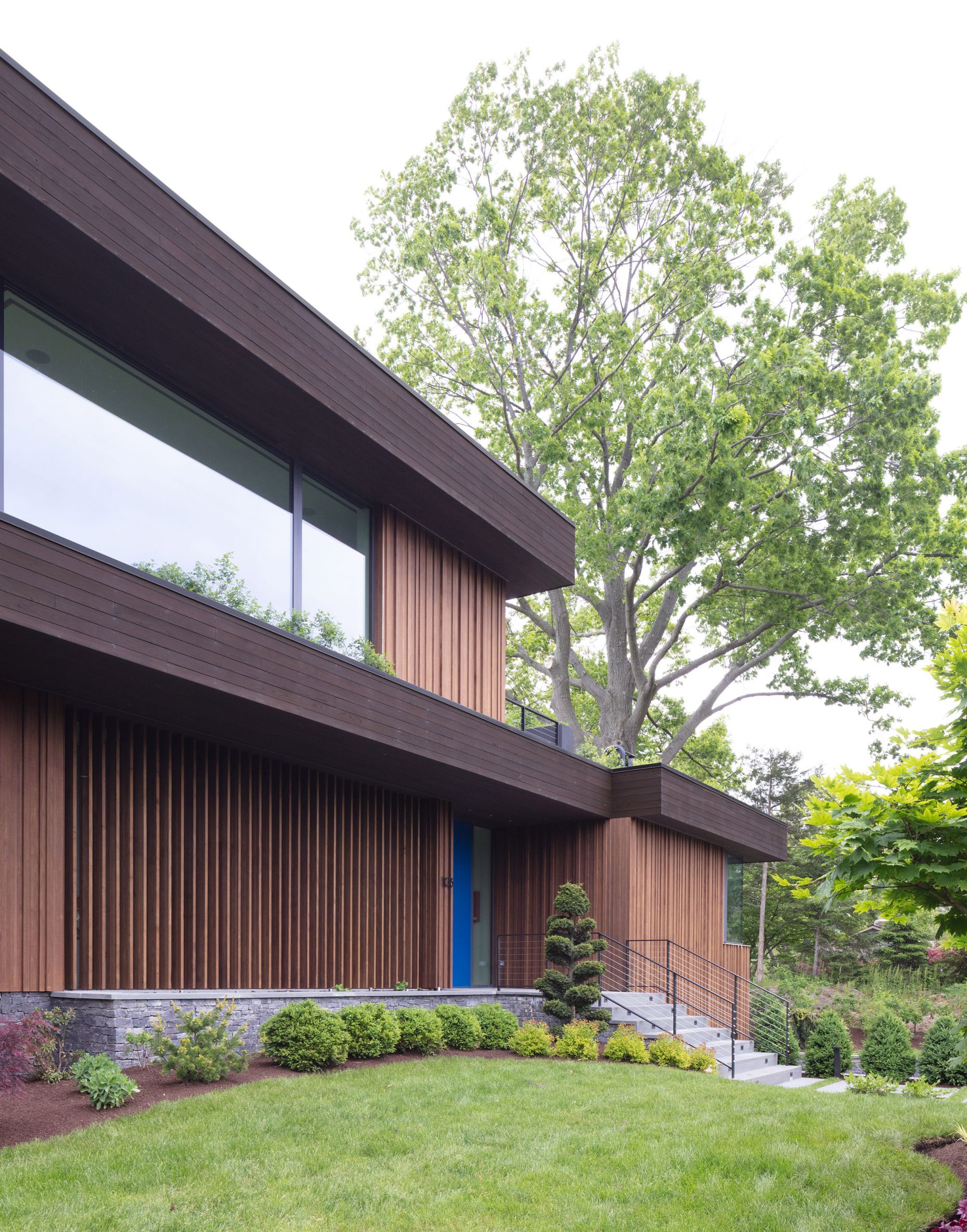 Exterior of a timber-clad house by Worrell Yeung with cantilevered roof planes and terraces