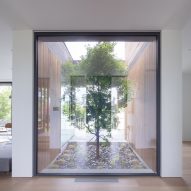 House interior with white walls and a large window looking out to a tree in a courtyard
