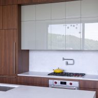 A kitchen with walnut and white glossy kitchen cabinets with white countertops