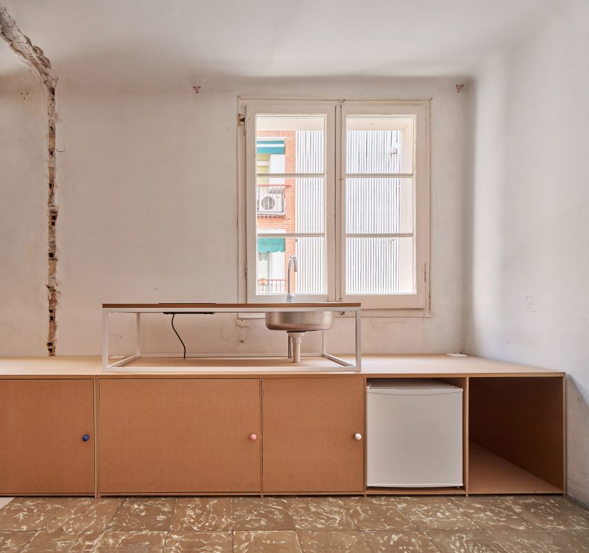 Gabinetes de madera bajos dentro de la cocina del apartamento con paredes blancas