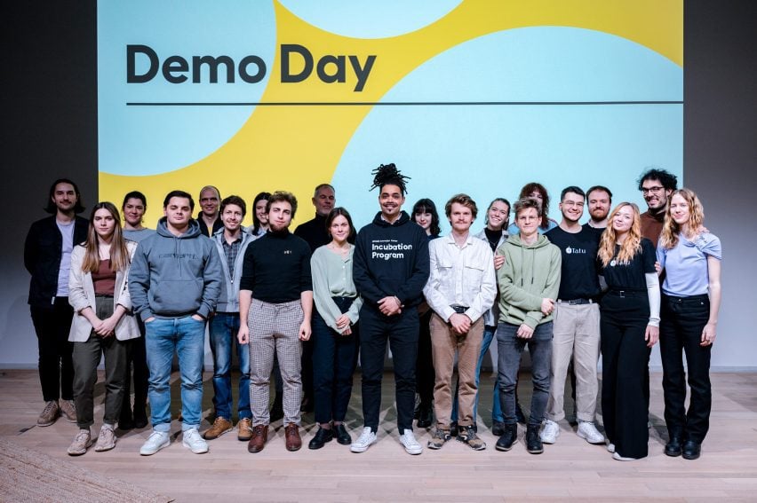 Students standing in front of a screen that says "Demo Day"