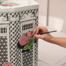 Photo of someone painting roses of Fornasetti furniture
