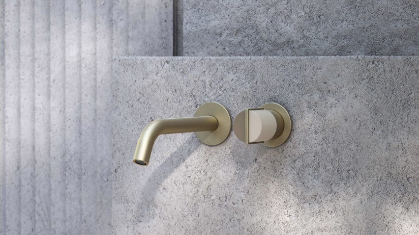 Gold tap and circular handle mounted on a concrete wall