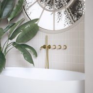 Gold wall-mounted shower head and handles next to a freestanding bath