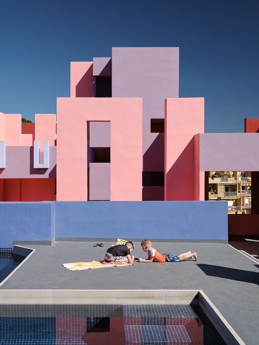 Children playing by the pool on the rooftop with pink structures in background