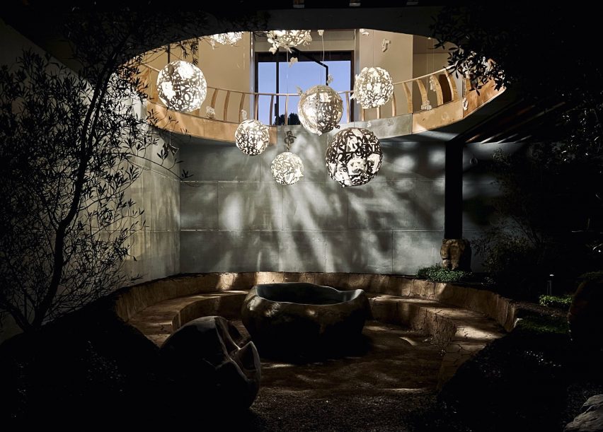 Concrete basement with a conversation pit and a circular opening in the ceiling with hanging orbs