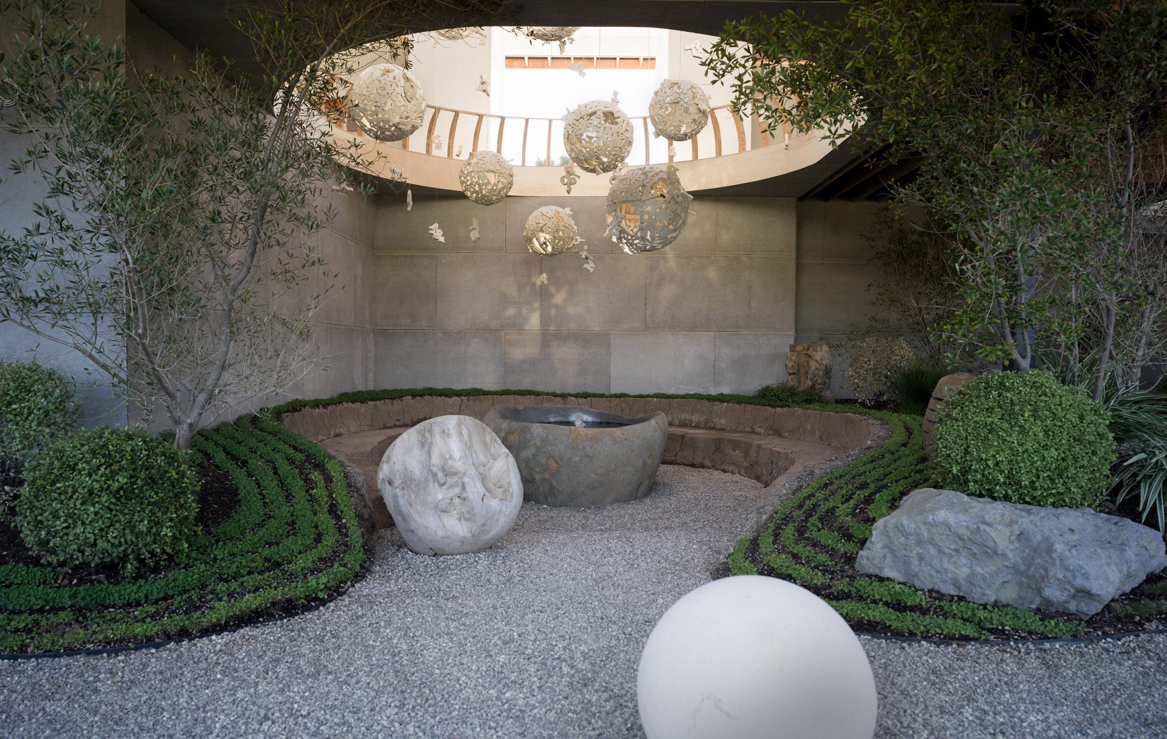 Circular opening an a ceiling with spheres hanging over a conversation pit