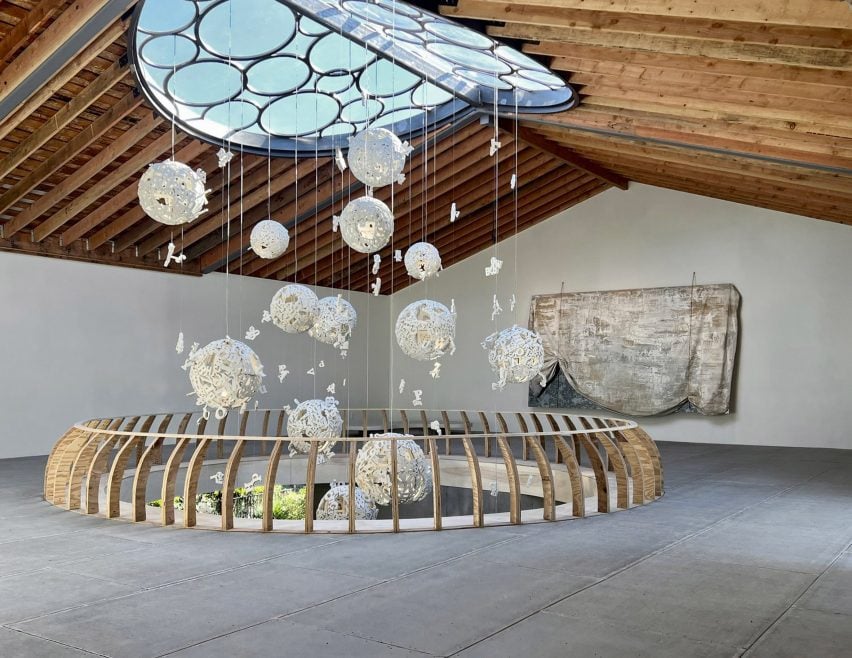 A room with an oculus in the ceiling and floor with hanging spheres