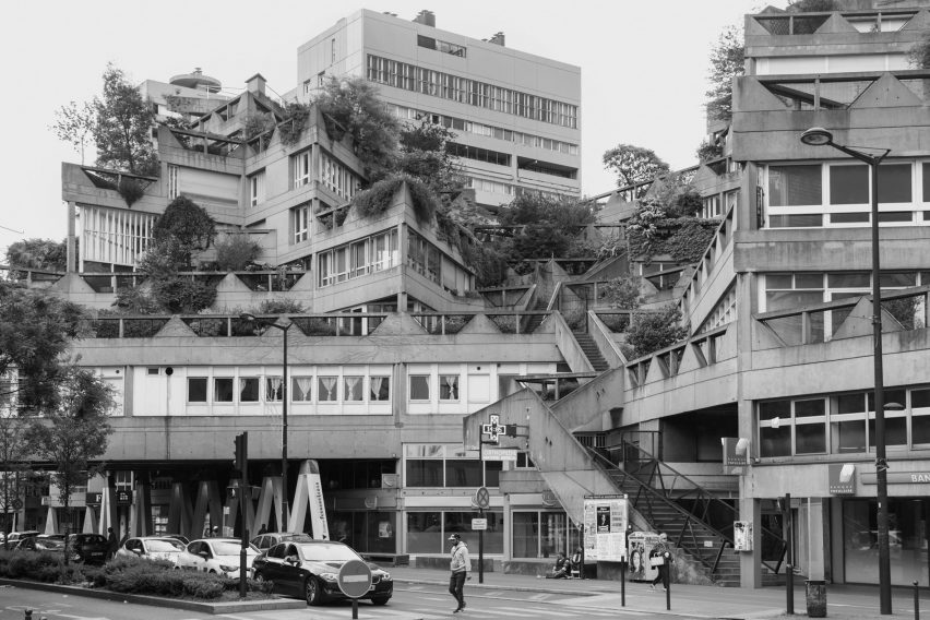 Fotografía en blanco y negro de un complejo de edificios residenciales y comerciales brutalista con bloques alineados en diferentes ángulos