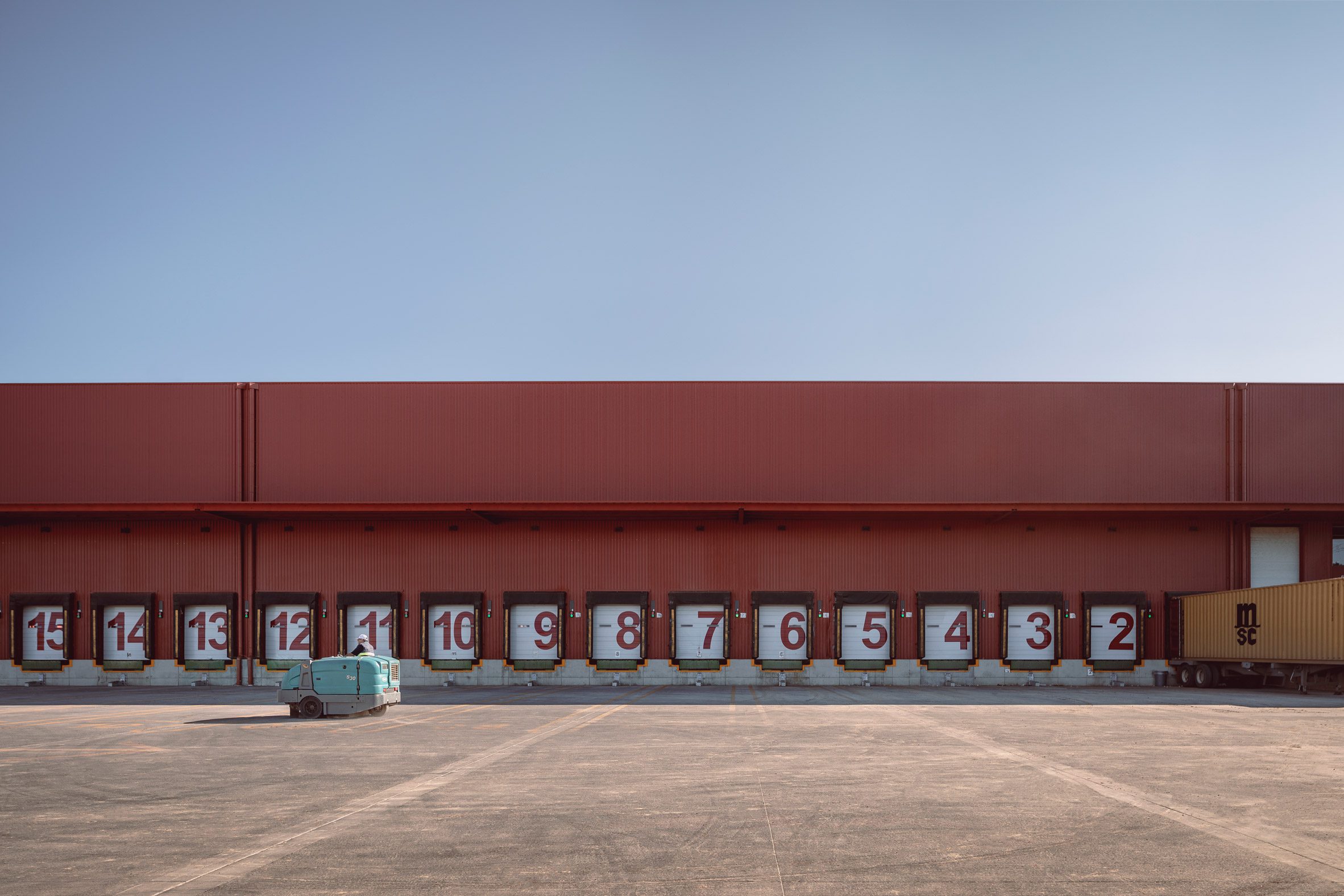 Warehouses with large numbers delineating their spaces at crimson-red building for Betterware