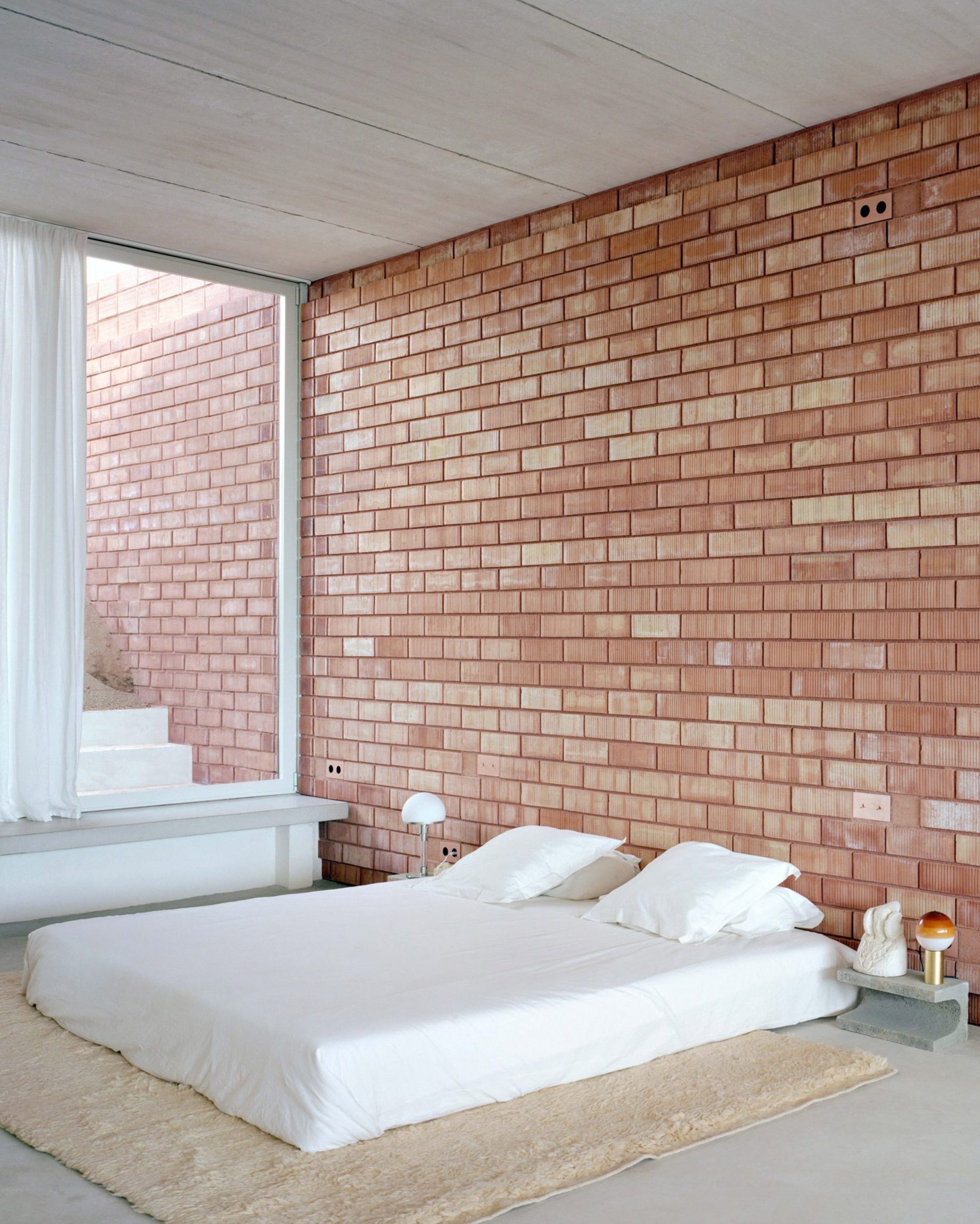 Bedroom with floor mattress and brick walls