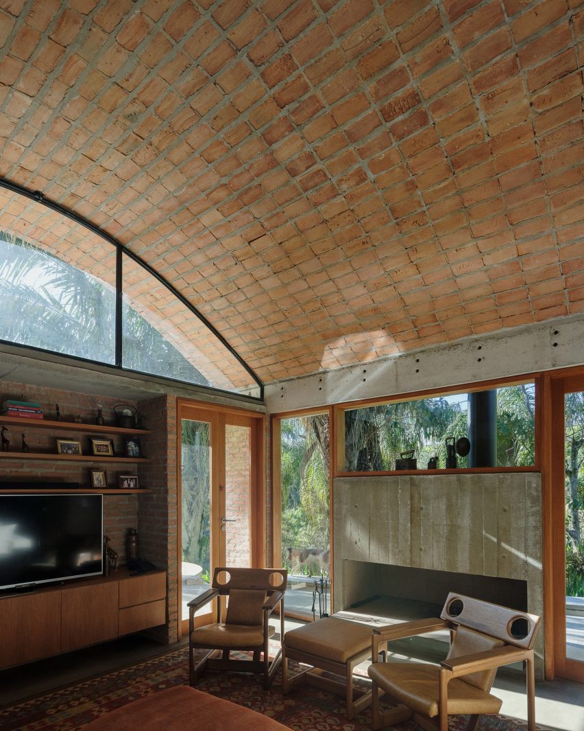 Board-formed concrete fireplace underneath vaulted brick ceiling in residential project by Denis Joelsons