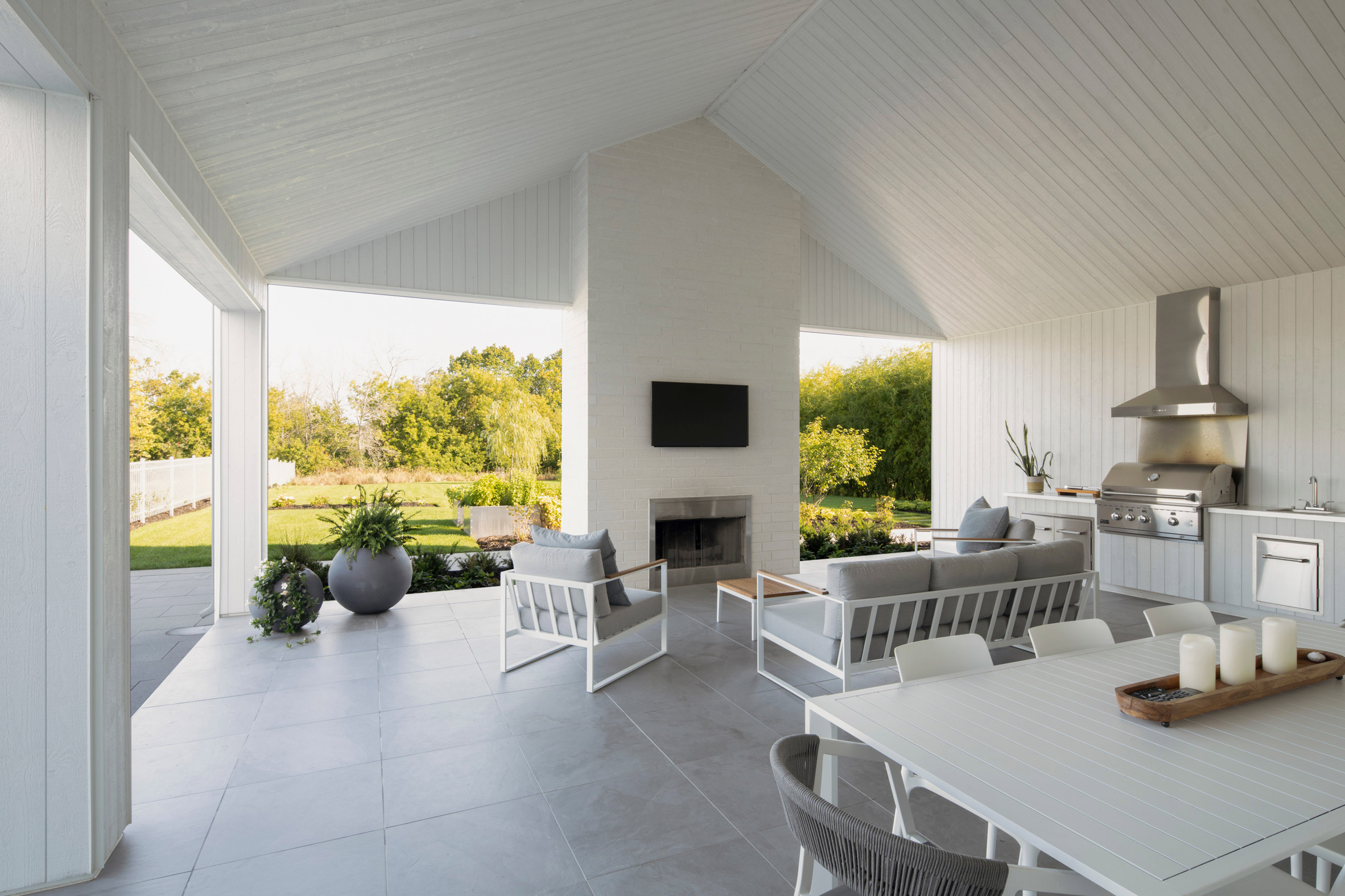 An open-plan living and dining space on a terrace with grey floors and white ceiling overhead
