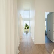 A hallway with timber floors, white walls and white curtains