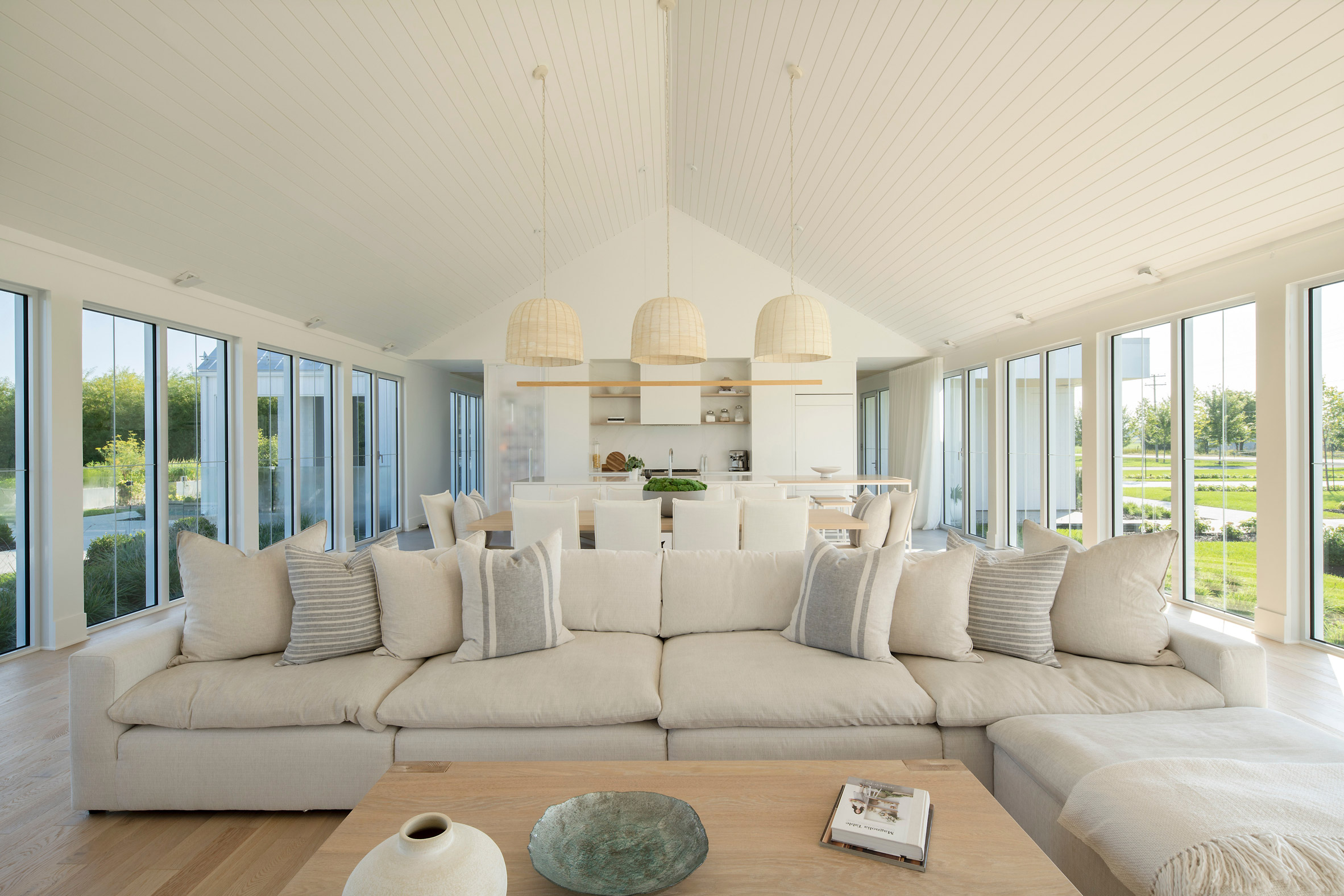 A living room with a pitched ceilings, white sofa with cushions and timber floors