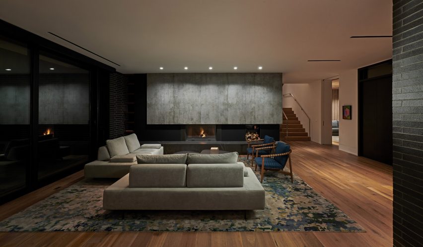 Interior of a living room with timber floors, floor-to-ceiling windows and grey sofas