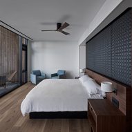 A bedroom with oak flooring, white walls, a white bed with a black headboard