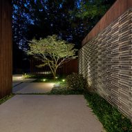 Exterior space with planting, stone paving and a tree lit by outdoor garden lights