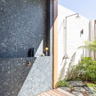 Bathroom with dark mosaic wall tiles and and outdoor shower