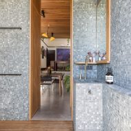 Bathroom with dark mosaic wall tiles, wood deck flooring and niche