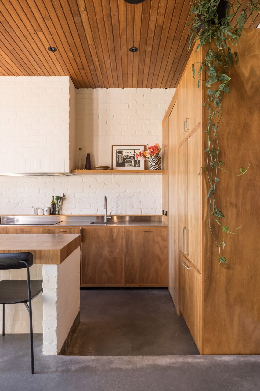 Kitchen with concrete flooring, white brick walls and wood cabinets