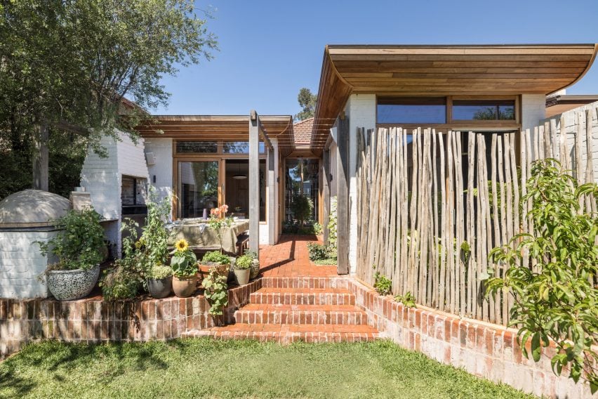 Jardín trasero de un bungalow con escalones de ladrillo que conducen a un patio y una ampliación de la casa