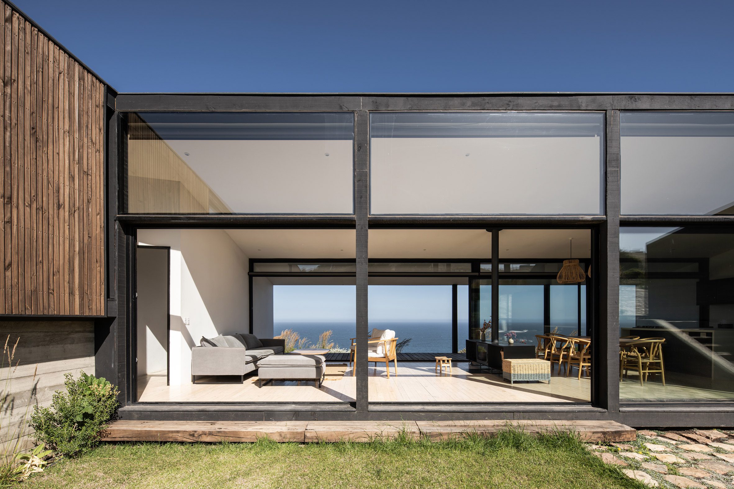 Outdoor garden of an open-plan home with large glass sliding doors overlooking the sea