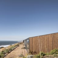 Timber-clad home with a sloping roof on a hillside overlooking the sea