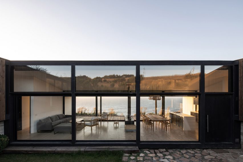 Exterior de una casa diáfana de una planta con paredes acristaladas con vistas al mar