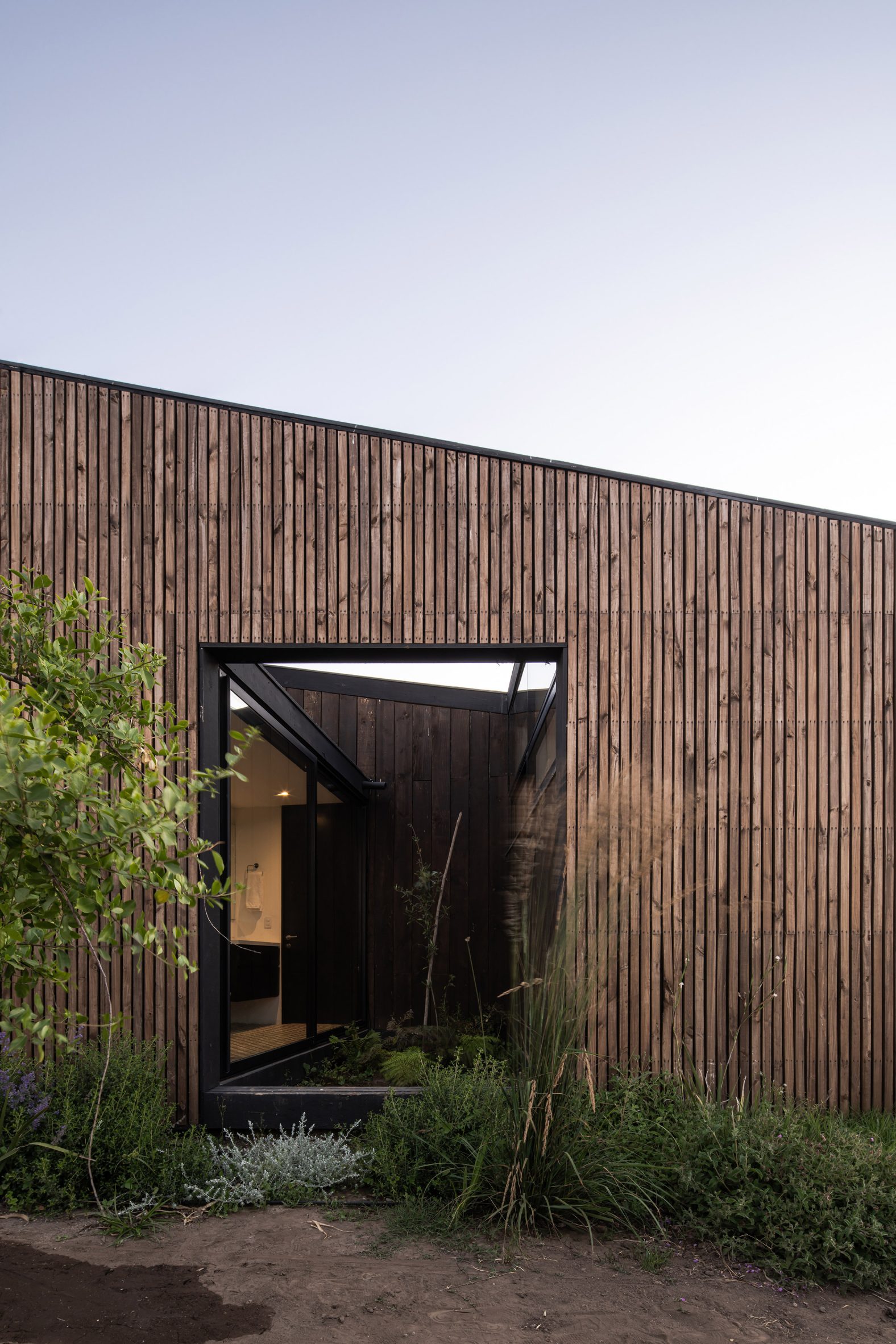 Exterior of a timber-clad home with a sloped roof and rectangular opening