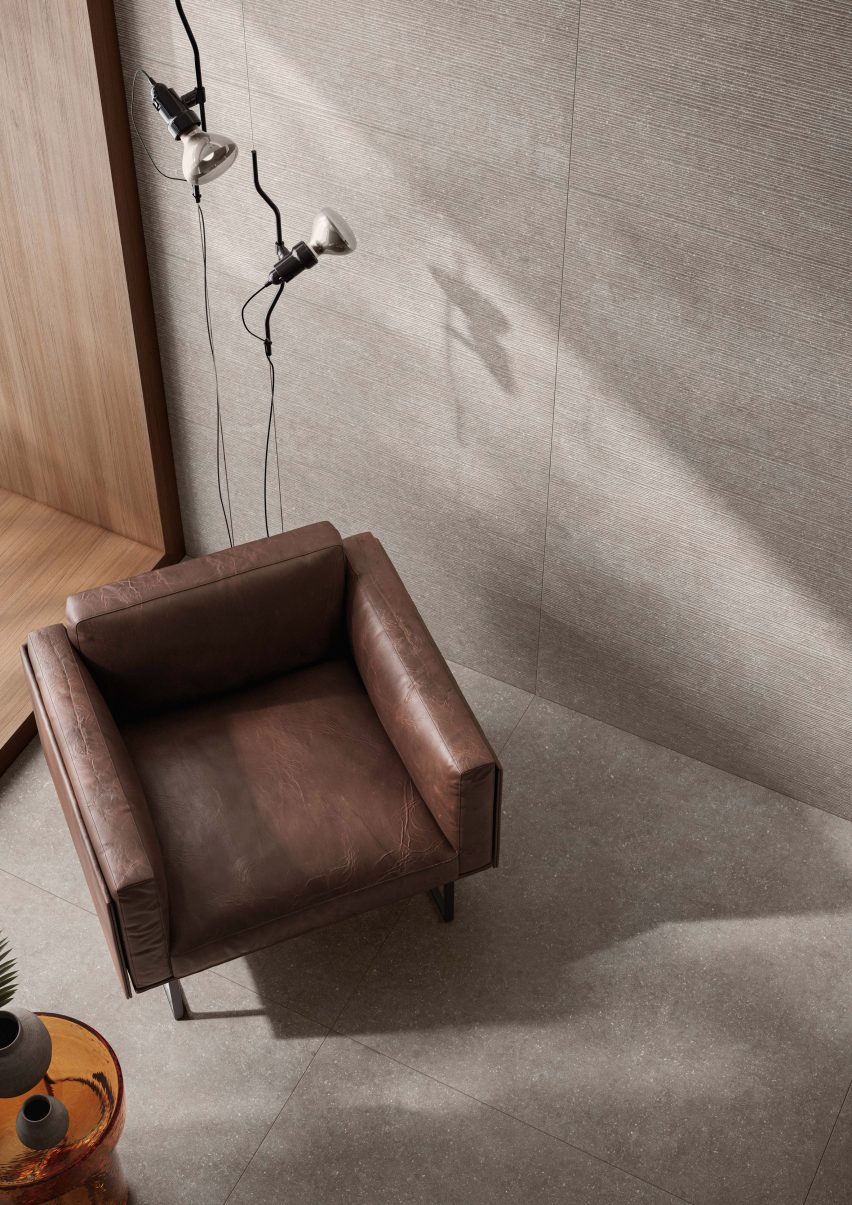 Corner of room with leather chair and grey tiles on walls and floor