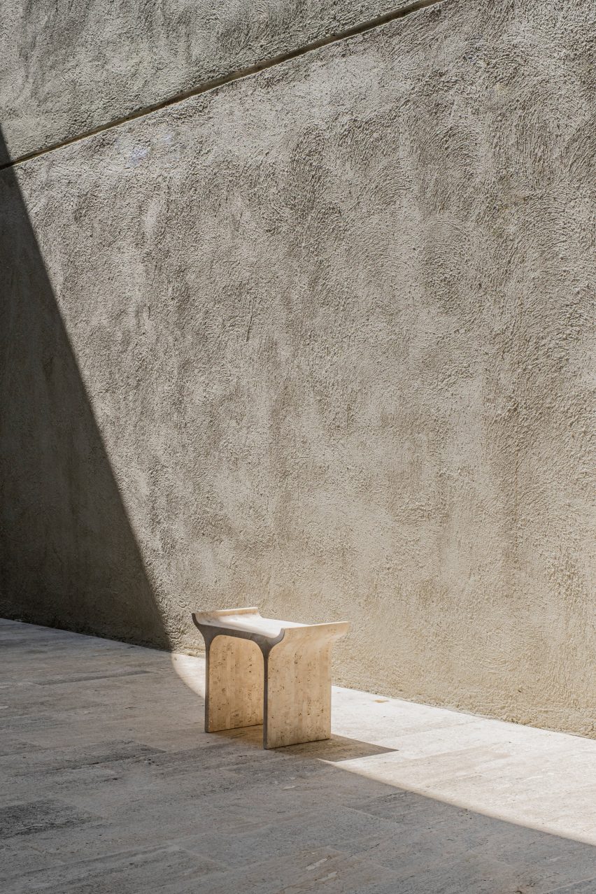 Travertine stool with brushed concrete wall