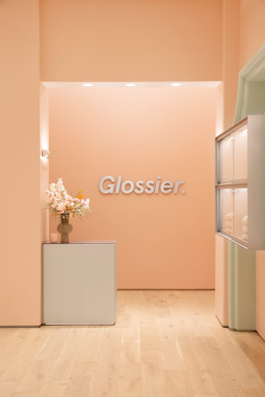 Glossier logo affixed to pale pink wall