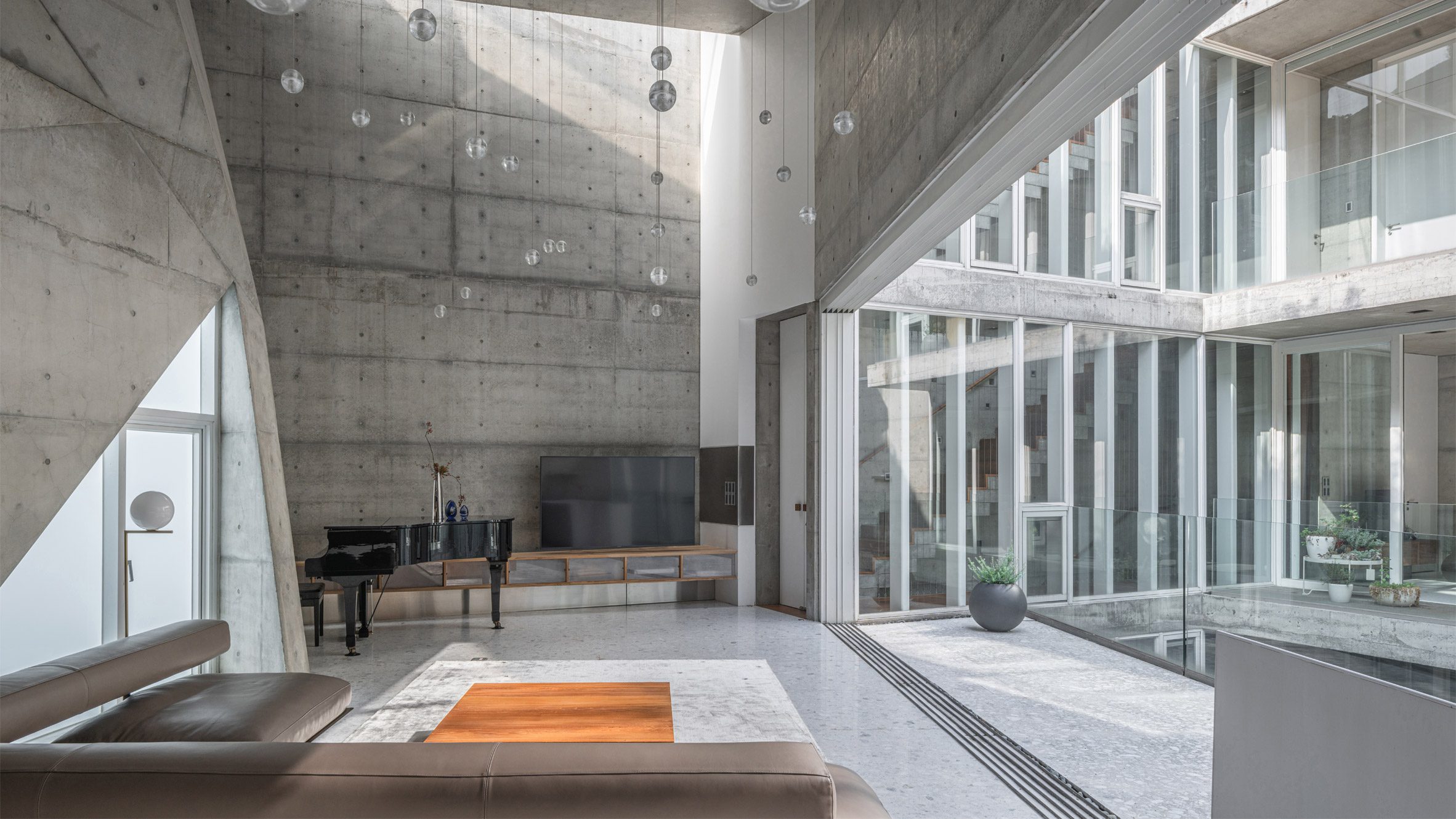 Concrete living space with lofty ceiling and large opening leading to a balcony overlooking a courtyard