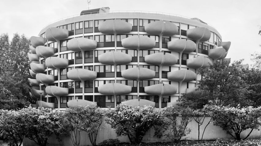 Black and white photo of a cylindrical multi-storey brutalist building with curved balconies staggered on the exterior