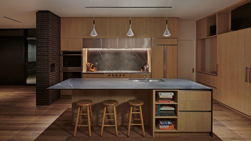 A kitchen with a central kitchen island with built-in storage, three pendant lights and wood wall cabinets