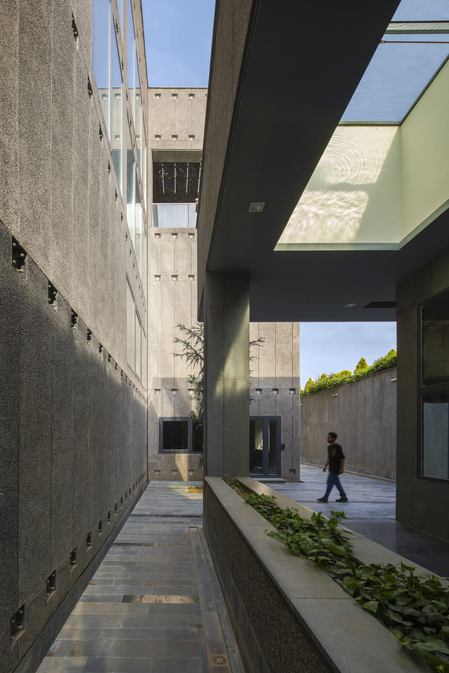 Person walking outside concrete building by Hooba Design Group