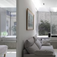 Partition wall dividing a living room with a grey sofa and a bedroom