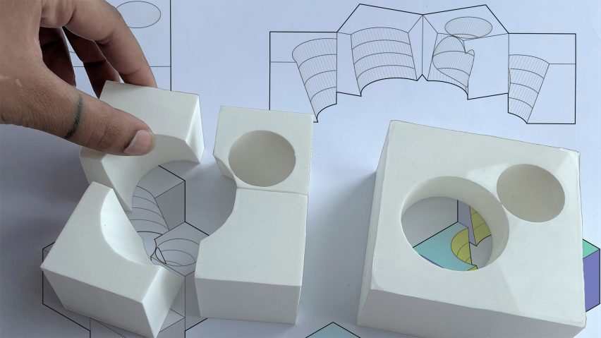 A hand assembling parts of a white, curved architectural model
